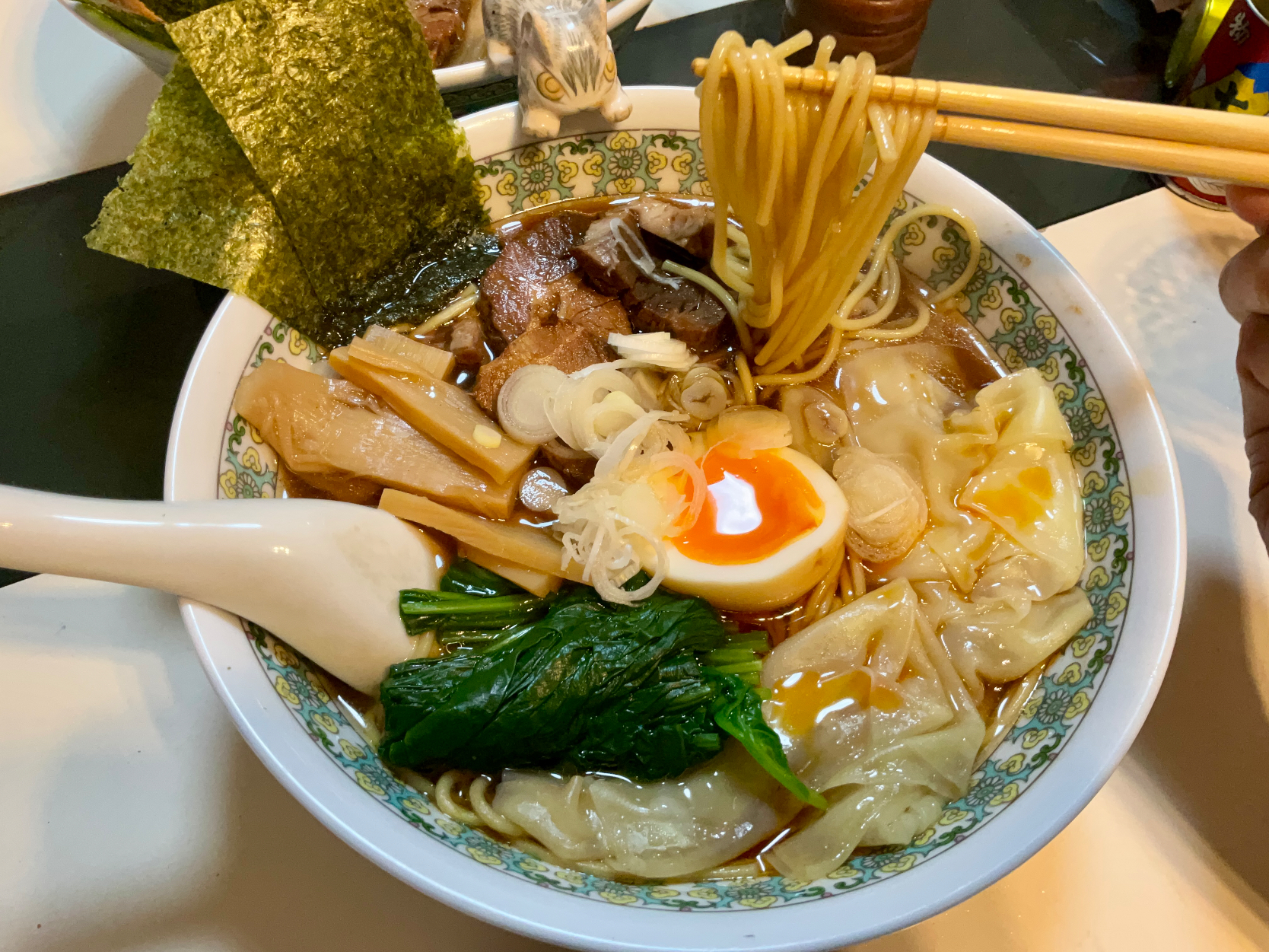 お家で作る醤油ワンタン麺
麺だけ買ってきてスープは自家製。昆布と粉の鰹節で出汁をとって、鶏ガラ、中華スープ、生姜などを入れ、煮切った醤油とお酒に絡ませ仕上げに胡麻油で香り漬けしました。
チャーシューは出来あいを買ってきて残してある自家製チャーシューの煮汁で再加工。